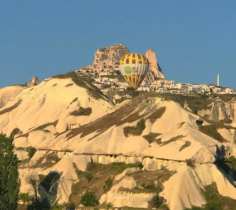 uchisar castle with a hot air balloon in front of it at cappadocia