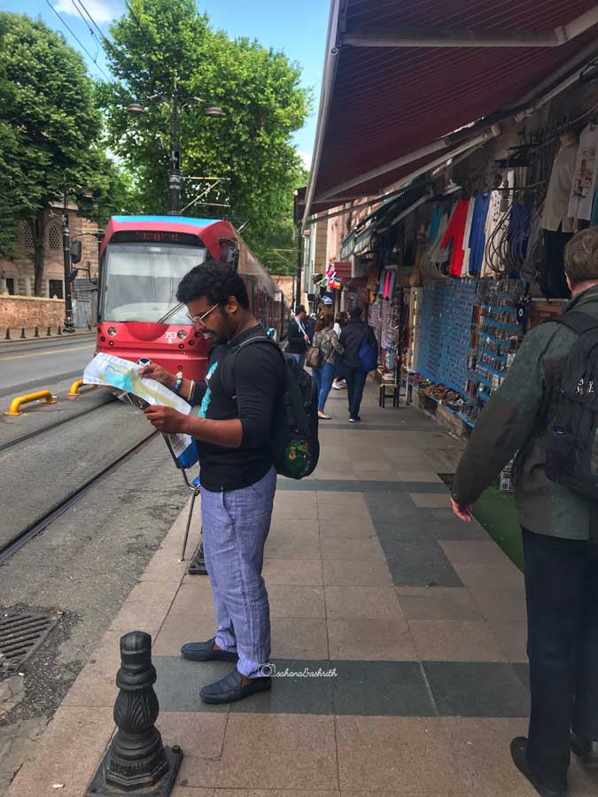 Indian traveller reading a paper mat by the sidde of tramway inIstanbul