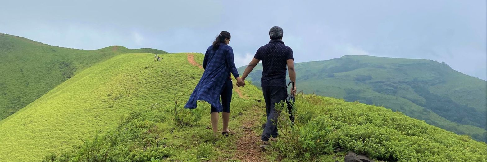 Indian couples walking holding hands on the green hills of western ghats