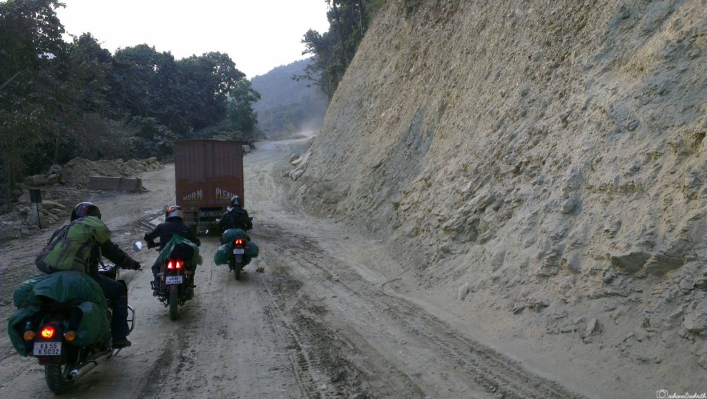 Indian bikers on a muddy road in Sikkim by the mountain side