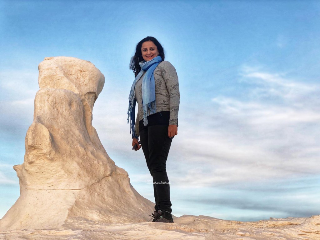 Indian woman traveller standing next to a limestone formation in the white desert