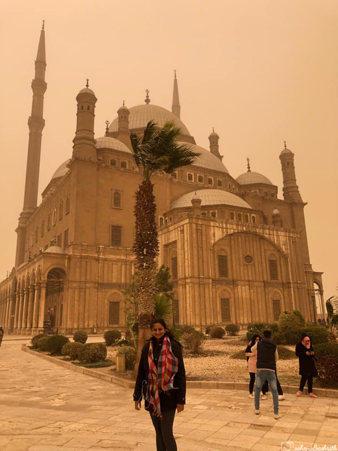 Blurry view of mosque from near covered in sand and sepia sky in Cairo citadel