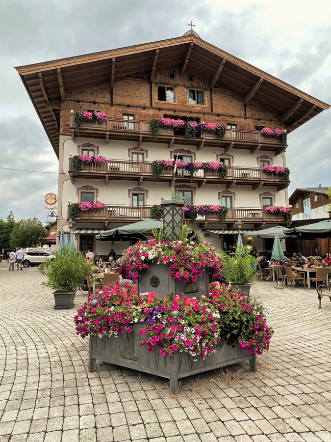 beautiful tyrolean style building with wooden cladding and balcony flowers at Kirchberg in Tirol