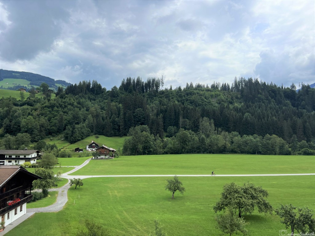 cycler in the green pasture lined with tyrolean houses near kirchberg
