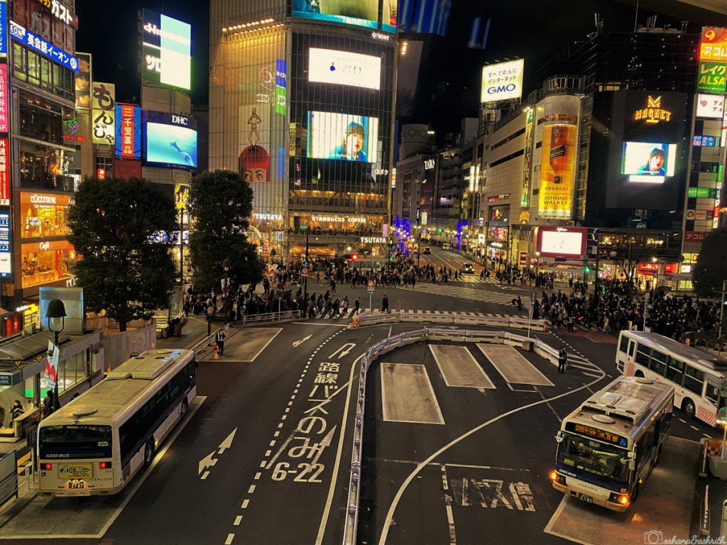 aerial view of Shibuya crossing with various modes of japan public transport at night