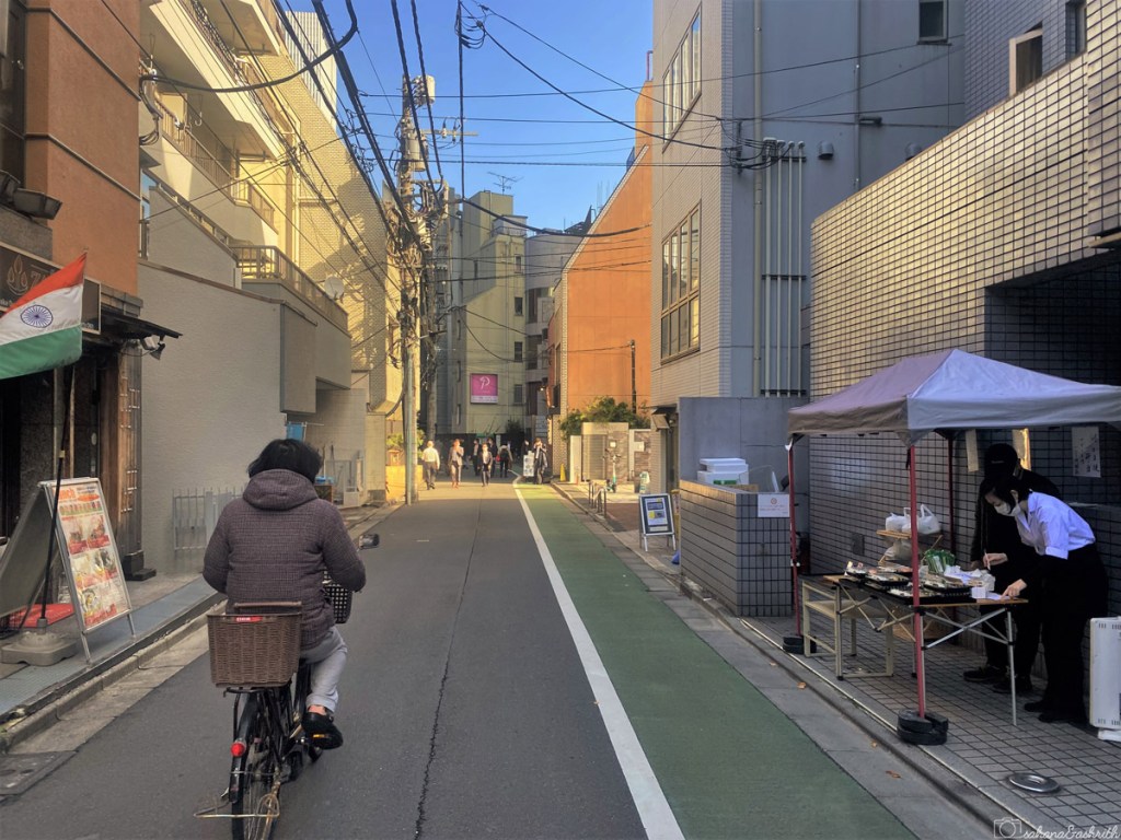 tokyo travel guide showing a quiet area of Akasaka with a woman on bicyle on the street and a another woman selling breakfast in the cart