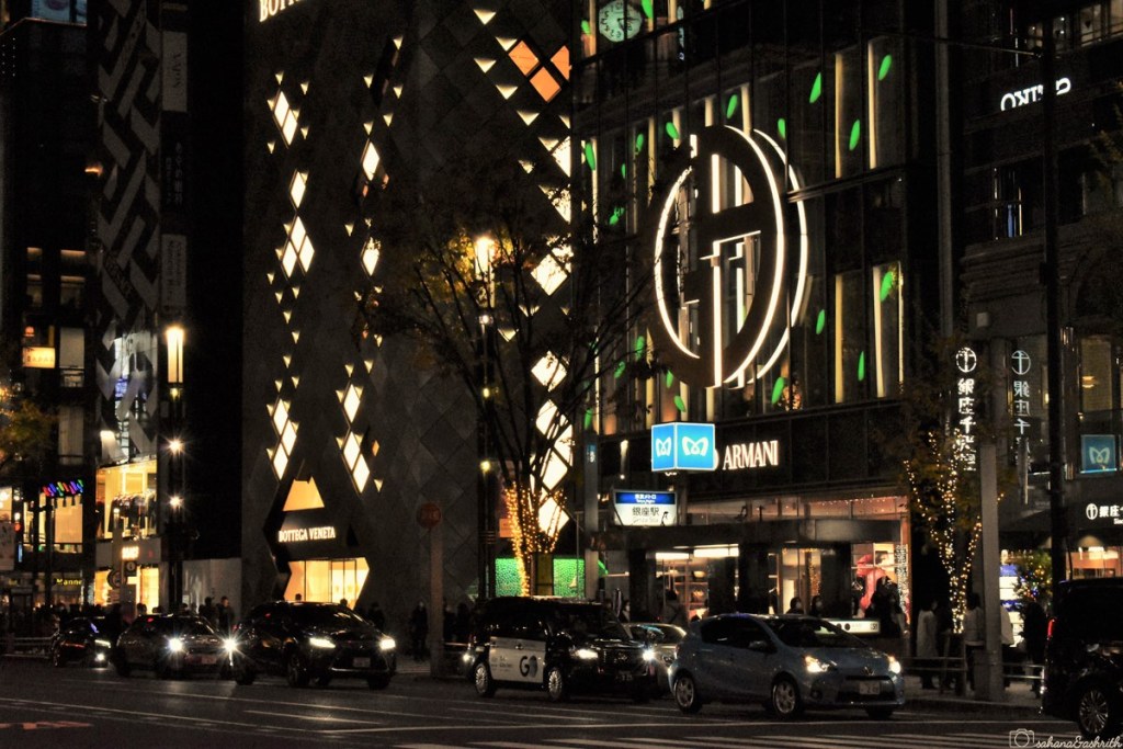 busy streets of ginza with luxury brand showroom on either side lit with fancy lights on a december night at tokyo