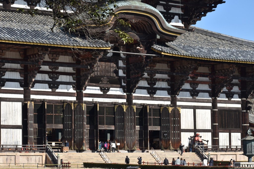 highly ornated todaji temple facade with dark wooden carvings on white wall at Nara