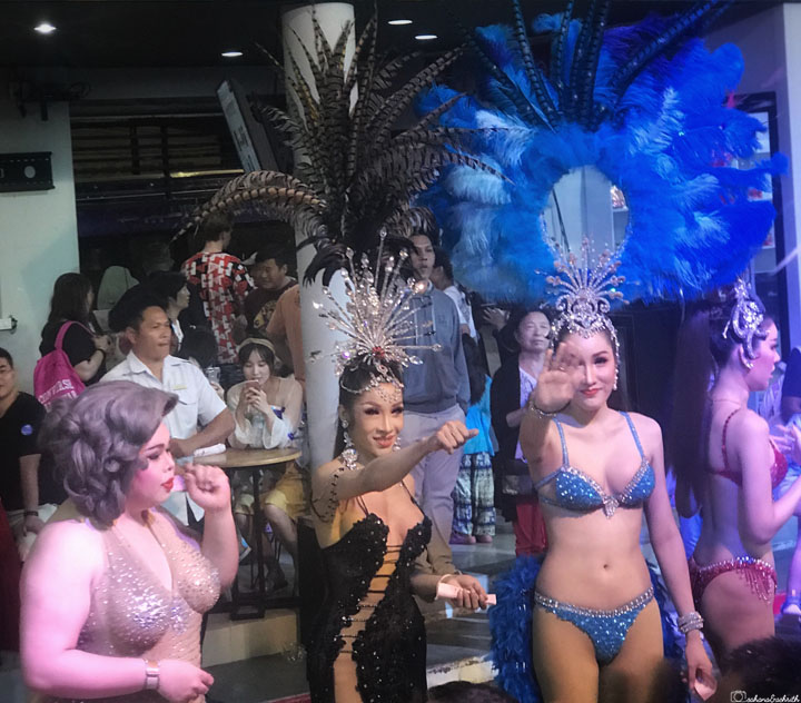 four lady boys in glamorous clothing waving at people for photo