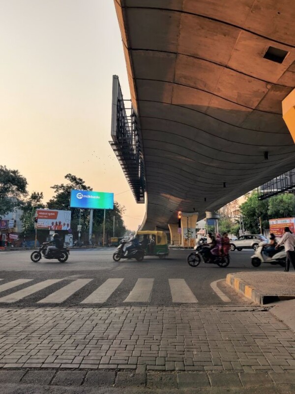 autorickshaw and bikes on the move under a flyover in a city of gujarat
