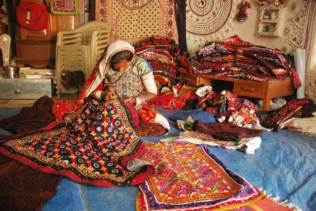 kutchi woman in traditional mirror work dress sewing craft
