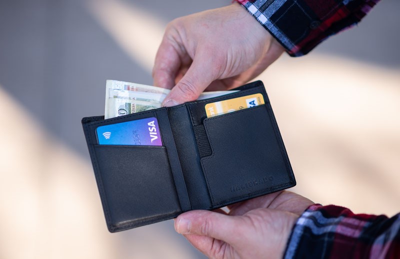 man taking money out of his wallet which has visa credit cards