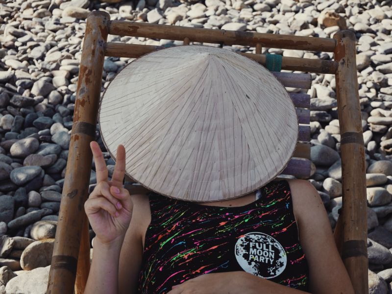 tourist wearing "full moon party" sticker with a hat on her face in thailand
