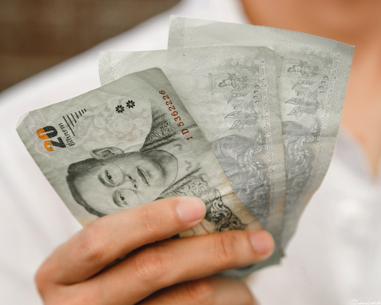 Girl holding thai bahts in hand paying for thailand tourist visa