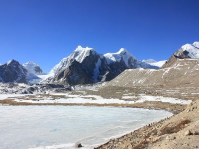 frozen lake of gurudongmar with himalayan mountains on one side and dry desert on other at Sikkim