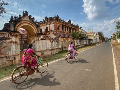 two woman on cycles wearing saree in chettinad, India