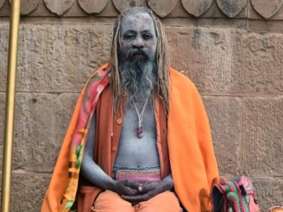 an indian saint sitting in yogic pose with ash on his face