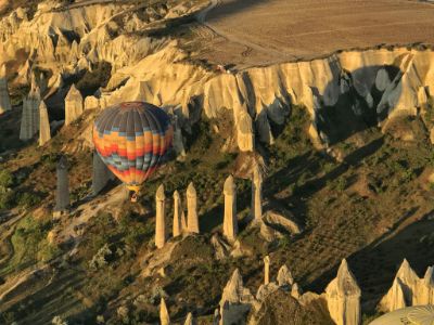 penis shaped formations and a hot air balloon flying above them in cappadocia