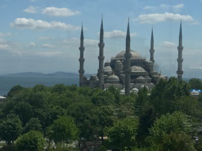 six tall minarets and domes of Blue mosque  surrounded by green and ocean in istanbul seen from above