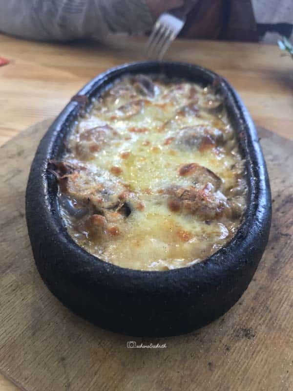 mushroom with kayseri cheese in a black flat bowl