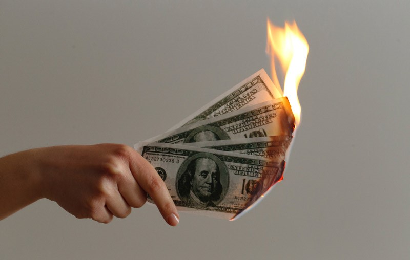 woman holding burning US Dollars