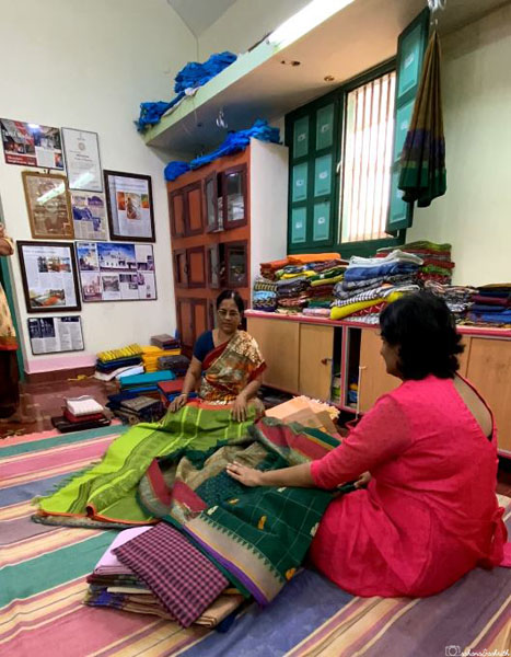 chettinad weaver displaying sarees to customer in a small room