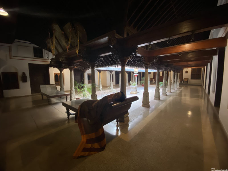 vacaywork author sahana in saree sleeping on marble antique furniture in corridor beside a courtyad in tarditional chettinad mansion converted to heritage hotel