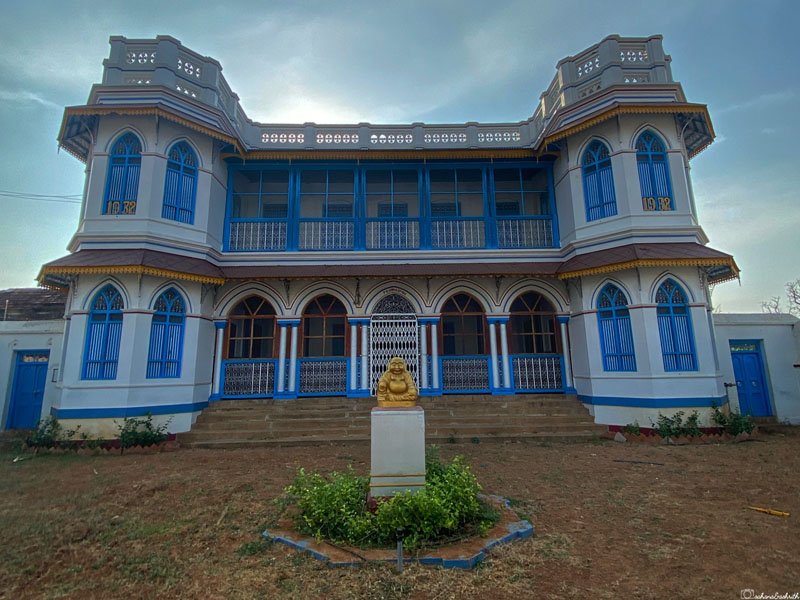 laughing buddha statue in front of the well maintained locked chettinad mansion