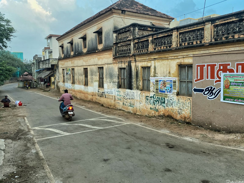 man on bike moving beside an abandoned chettinad mansion at karaikudi road