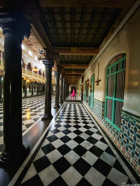 corridors of lakshmi vilas palace in chettinad with black and white chekered flooring and walls cladded with colourful belgian tiles
