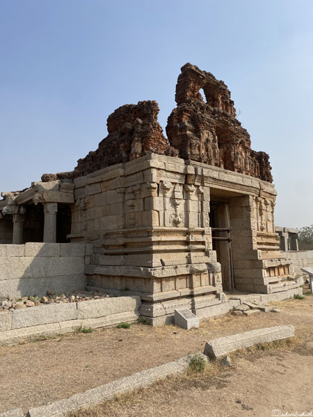 Sri Vaishnava temple entrance: stone base with relief sculptures and ruined gopuram revealing brick