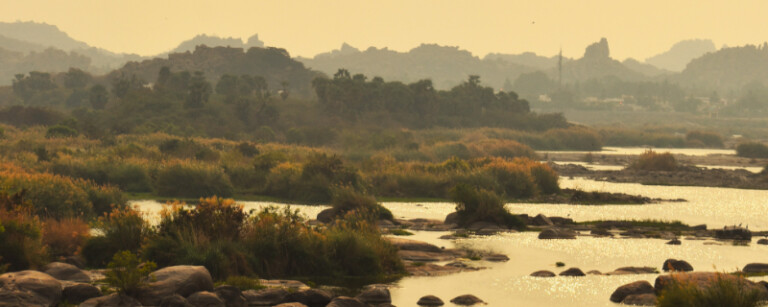 tungabhadra river during sunset with fog dotted with vegetation near anegundi
