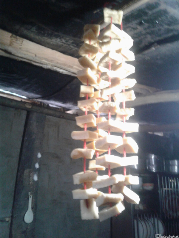 Strips of hard Chhurpi cheese strung up to dry in a rustic kitchen, hanging from the ceiling.
