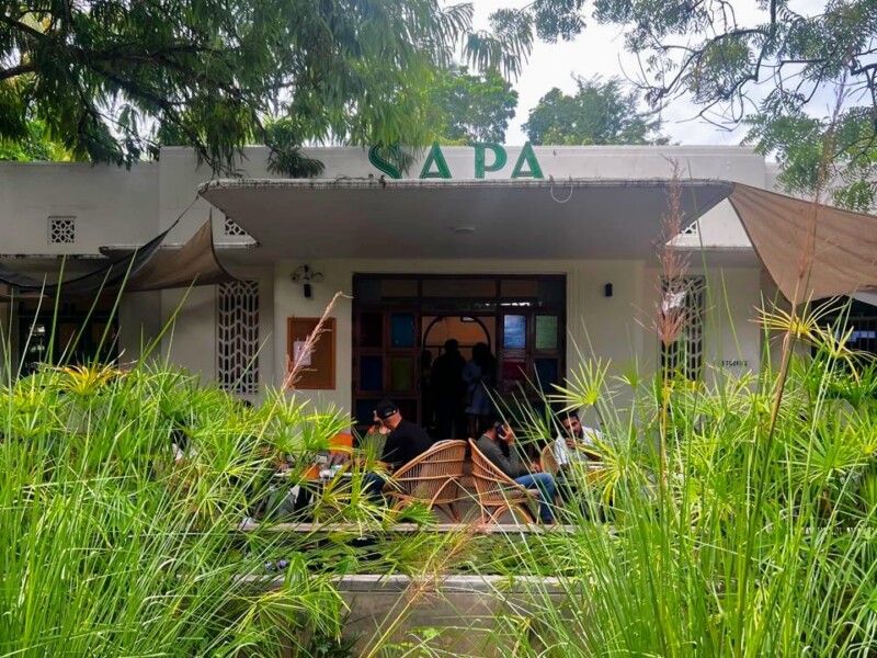 The front view of Sapa with greenery and customers seated outside, showing the cafe's entrance.