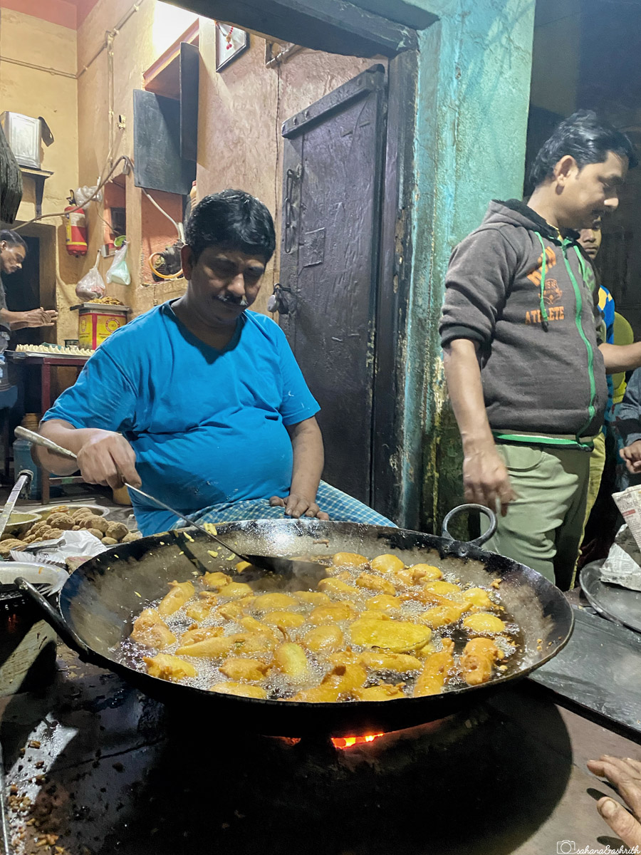 A vendor in Varanasi frying freshly made bajji in hot oil, creating a batch of golden, crispy treats.