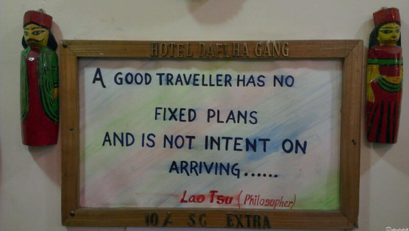 A framed quote at Hotel Daflha Gang reads, "A good traveller has no fixed plans and is not intent on arriving," by Lao Tzu, flanked by decorative wooden figures