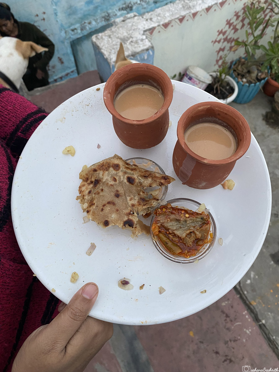 A plate with paratha, pickle, and tea in Varanasi.