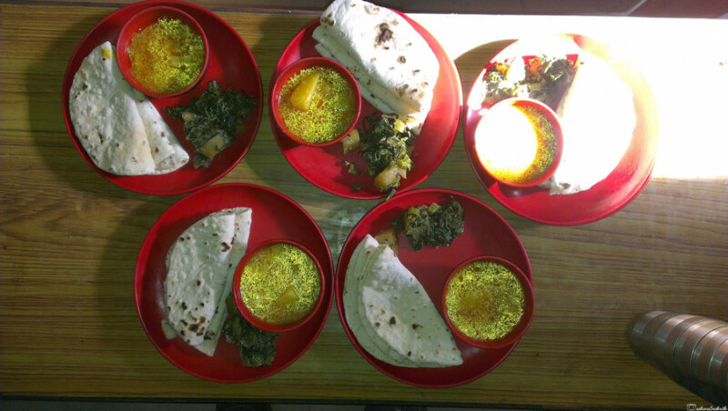 Traditional Sikkimese meals are served on red plates, consisting of sel roti, saag leaf curries, and vegetables.