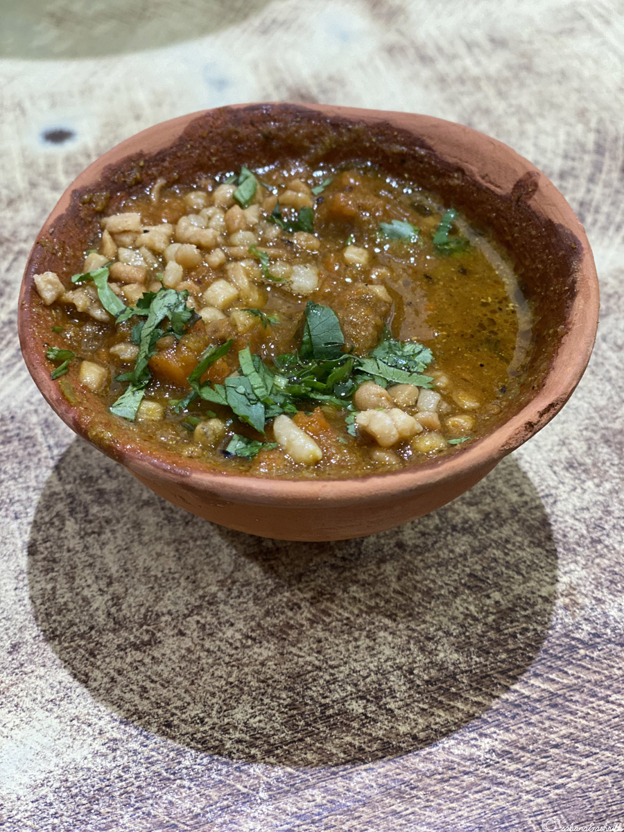 A bowl of Tamatar in earthen pot Chaat garnished with coriander in Varanasi