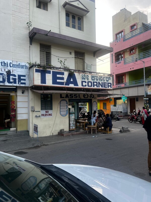 The exterior of Tea Corner with customers sitting on benches outside, located on a street corner.