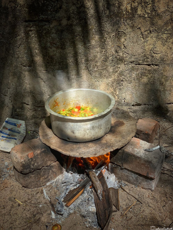 A pot of food cooking on an open fire outdoors.