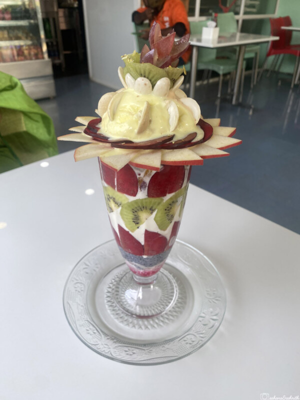 Tall glass parfait with layered fruits and ice cream

