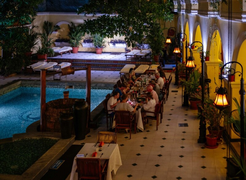 Elegant dining setup by a pool with people dining