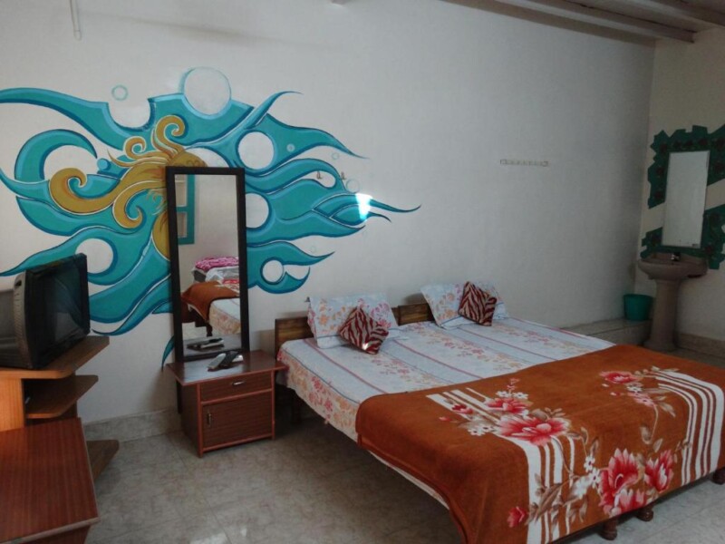 A cosy bedroom with colourful wall art, a double bed, and a TV.
