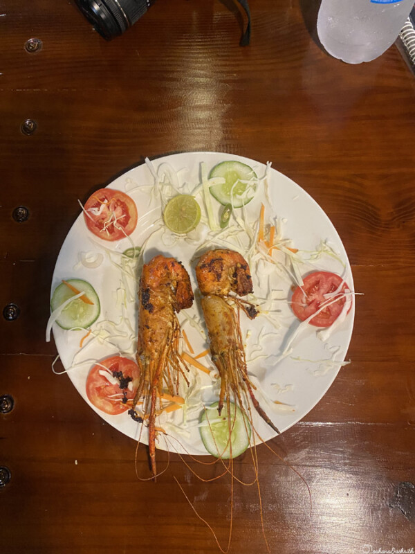 Plate with grilled prawns, sliced tomatoes, cucumbers, and shredded cabbage
