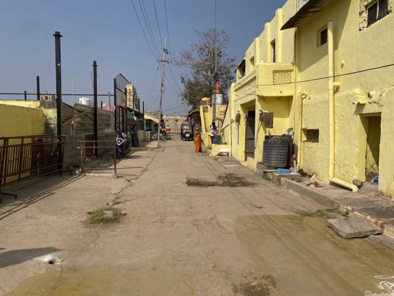 A quiet street in Hampi with yellow-painted buildings and people walking.