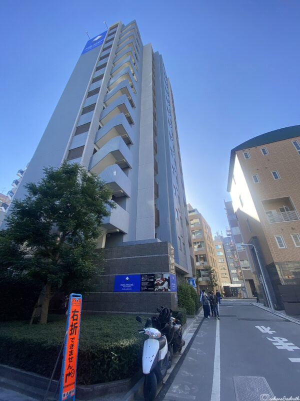 Tall, modern business hotel building with clear blue skies, viewed from street level in japan