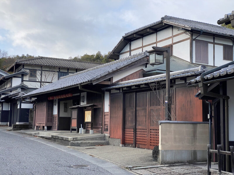 Street view of traditional Japanese machiyab uildings with wooden facades and tiled roofs, under a cloudy sky