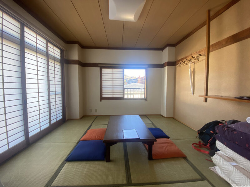 A minimalistic Japanese-style tatami room with a low wooden table and cushions on the floor.