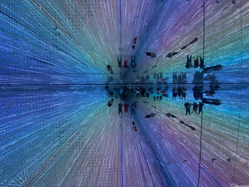 Interactive light installation with reflections of people and rainbow lights creating an illusion of endless space at team lab planets tokyo